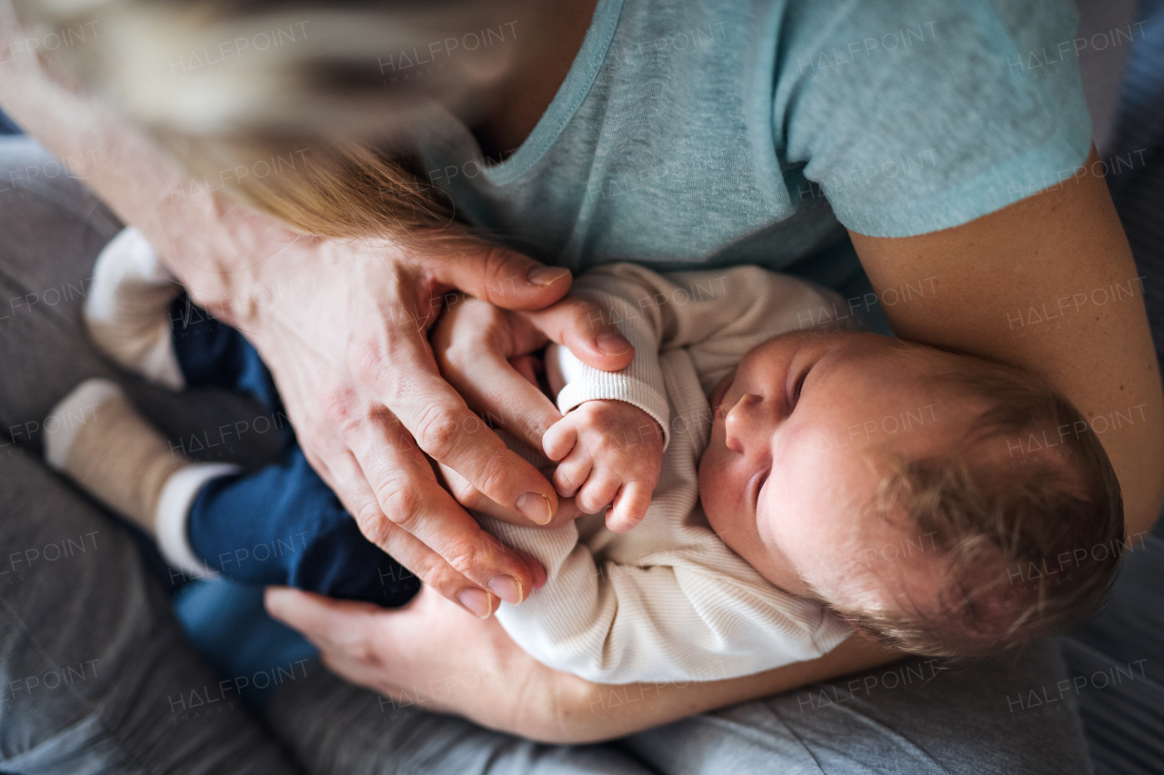 A midsection of young parents with a newborn baby at home, top view.