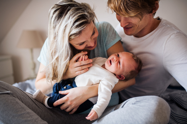 Beautiful young parents holding a newborn baby at home.