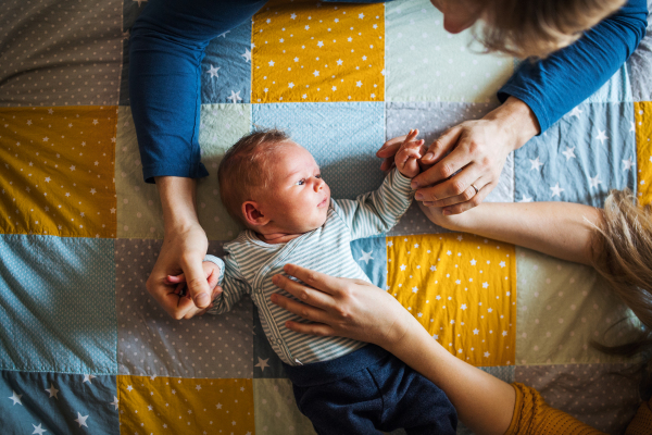 A top view of a newborn baby lying on bed on a quilted blanket at home.