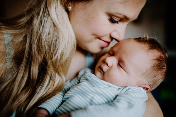 A beautiful young mother holding a newborn baby at home.