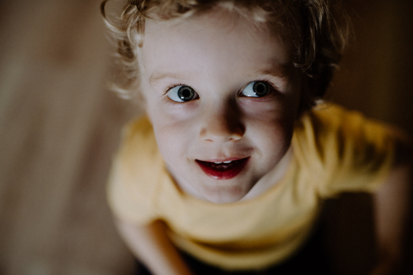 A top view of a toddler boy at home, looking up. A close-up.