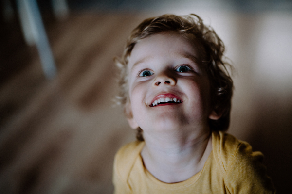 A top view of a toddler boy at home, looking up. A close-up.