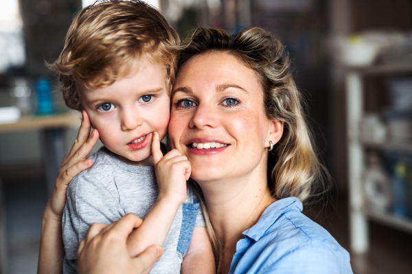 A happy mother with a toddler son indoors at home, playing. Copy space.