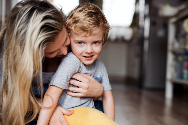 A happy mother with a toddler son indoors at home, playing. Copy space.