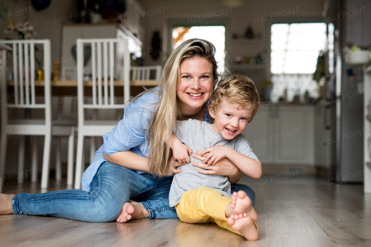 A happy mother with a toddler son indoors at home, playing. Copy space.