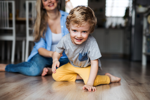 A mother with a happy toddler son indoors at home, playing.