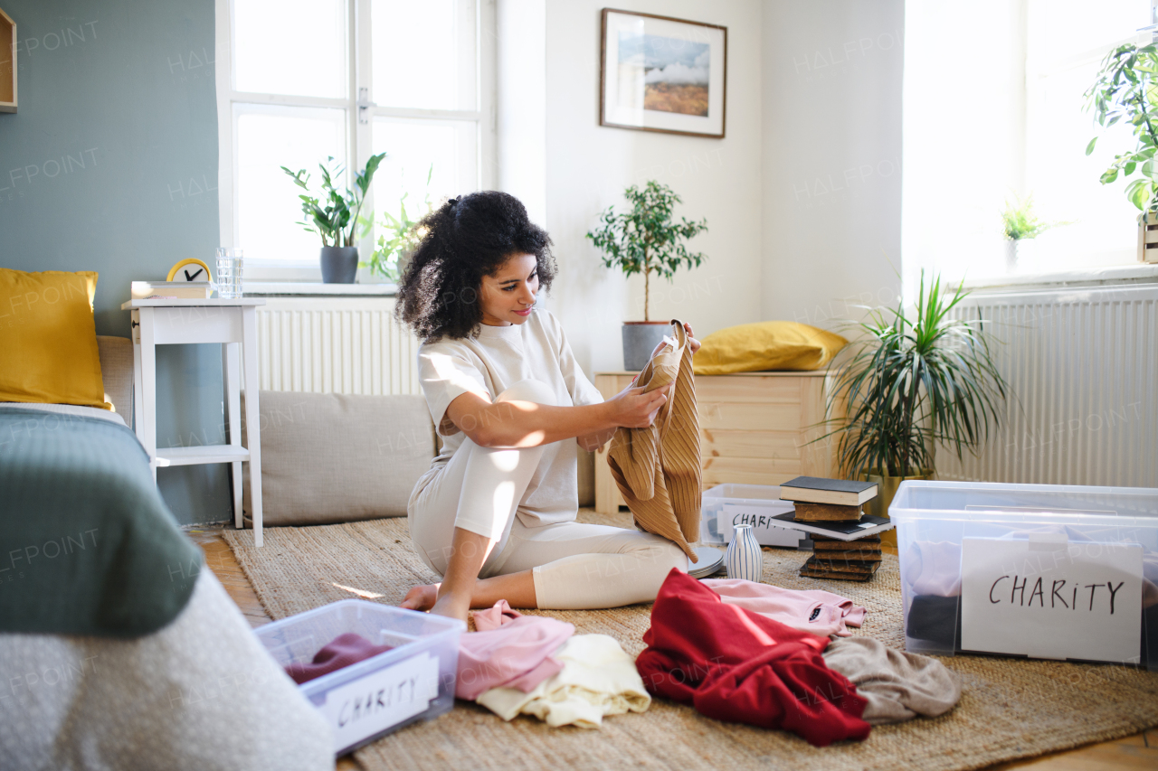 Happy young woman sorting wardrobe indoors at home, charity donation concept.