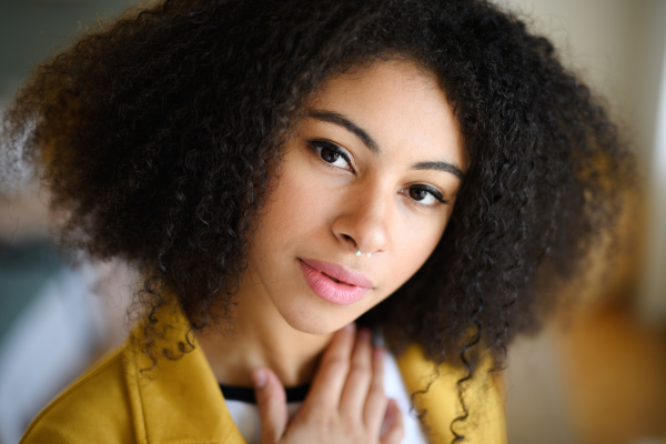 Close-up front view portrait of beautiful young woman indoors, looking at camera.