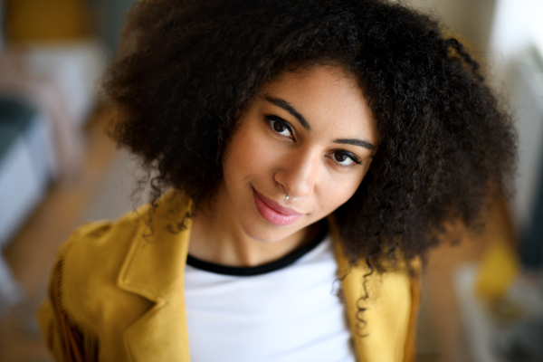 Close-up front view portrait of young woman indoors, looking at camera.