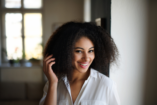 Close-up front view portrait of young woman indoors, looking at camera.