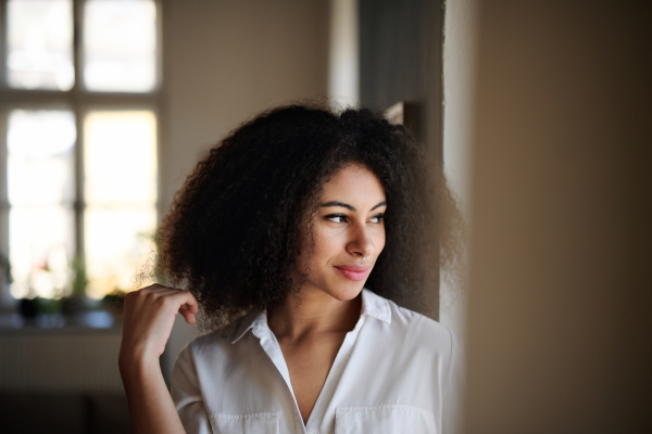 Close-up portrait of young woman indoors, feeling happy and contented.