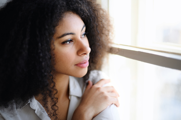 Close-up front view portrait of young woman indoors, daydreaming.