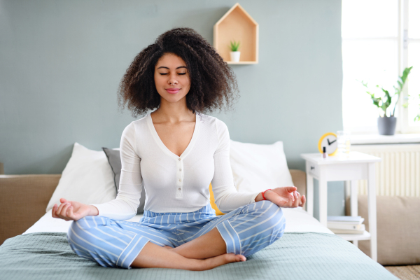 Portrait of relaxed young woman indoors at home, doing yoga exercise.