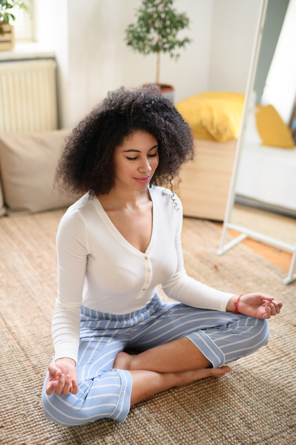 A portrait of young woman indoors at home, doing yoga exercise on floor.