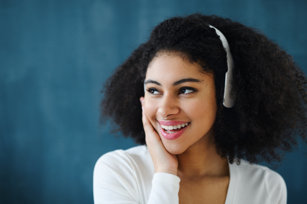 A portrait of young woman with headphones indoors at home, listening to music.