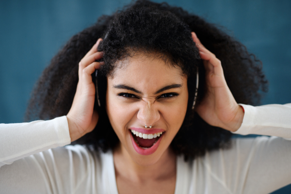 Close-up portrait of young woman with headphones indoors at home, listening to music.