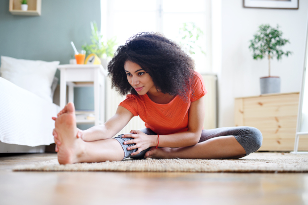 Happy young woman indoors at home, doing exercise. Sport concept.