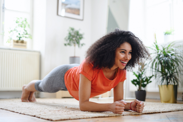 Happy young woman indoors at home, doing exercise. Sport concept.