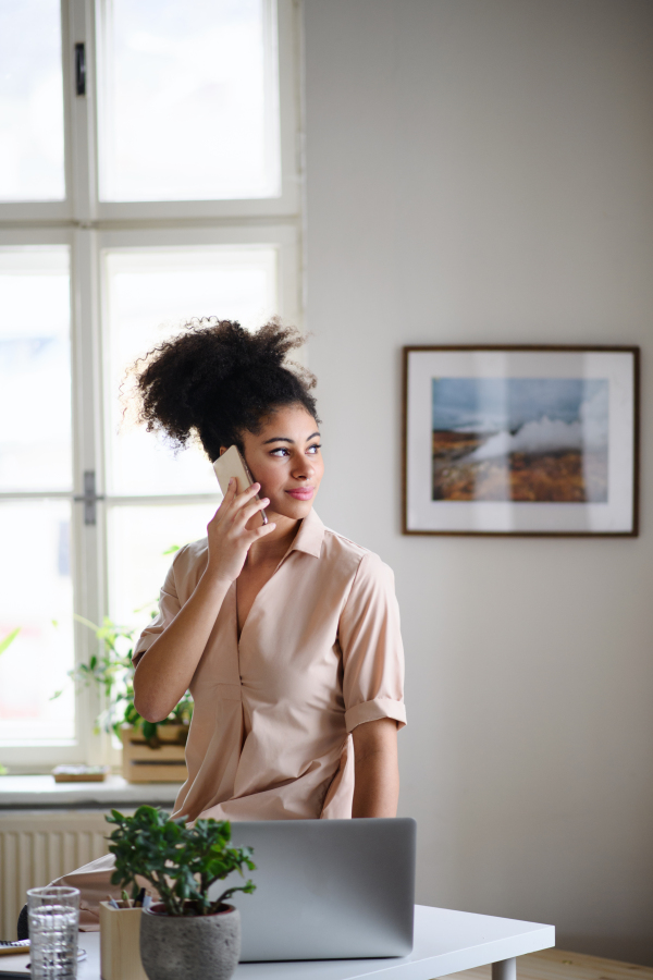 Happy young woman student with laptop and smartphone working indoors at home, home office concept.