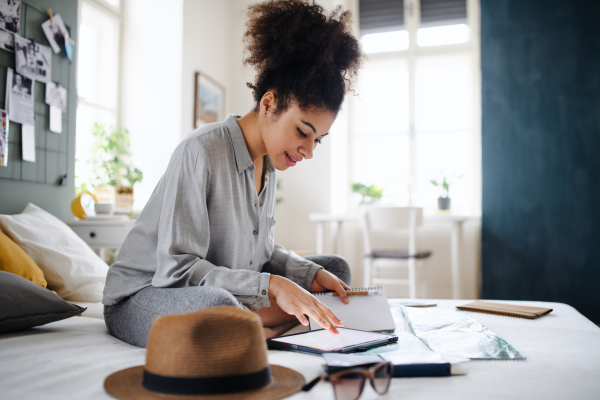 Happy young woman with tablet and map indoors at home, planning traveling trip.