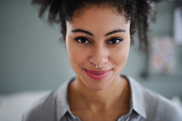 Close-up front view portrait of beautiful young woman indoors, looking at camera.