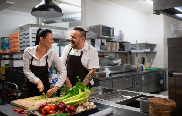 A chef teaching how to cook, cutting vegetables indoors in commercial kitchen.