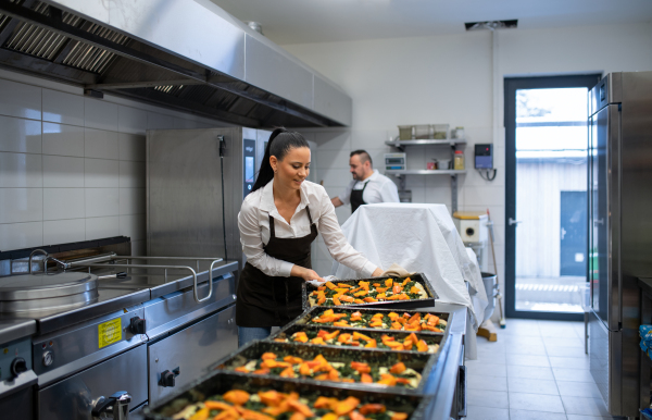 A chef and cook working on their dishes indoors in restaurant kitchen.