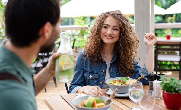 Happy couple sitting at the table outdoors on terrace restaurant, talking.