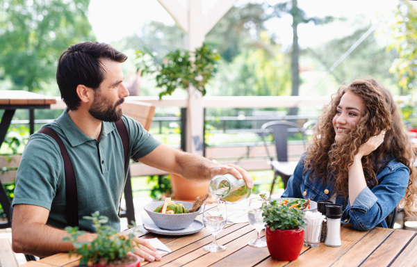 Happy couple sitting at the table outdoors on terrace restaurant, talking.