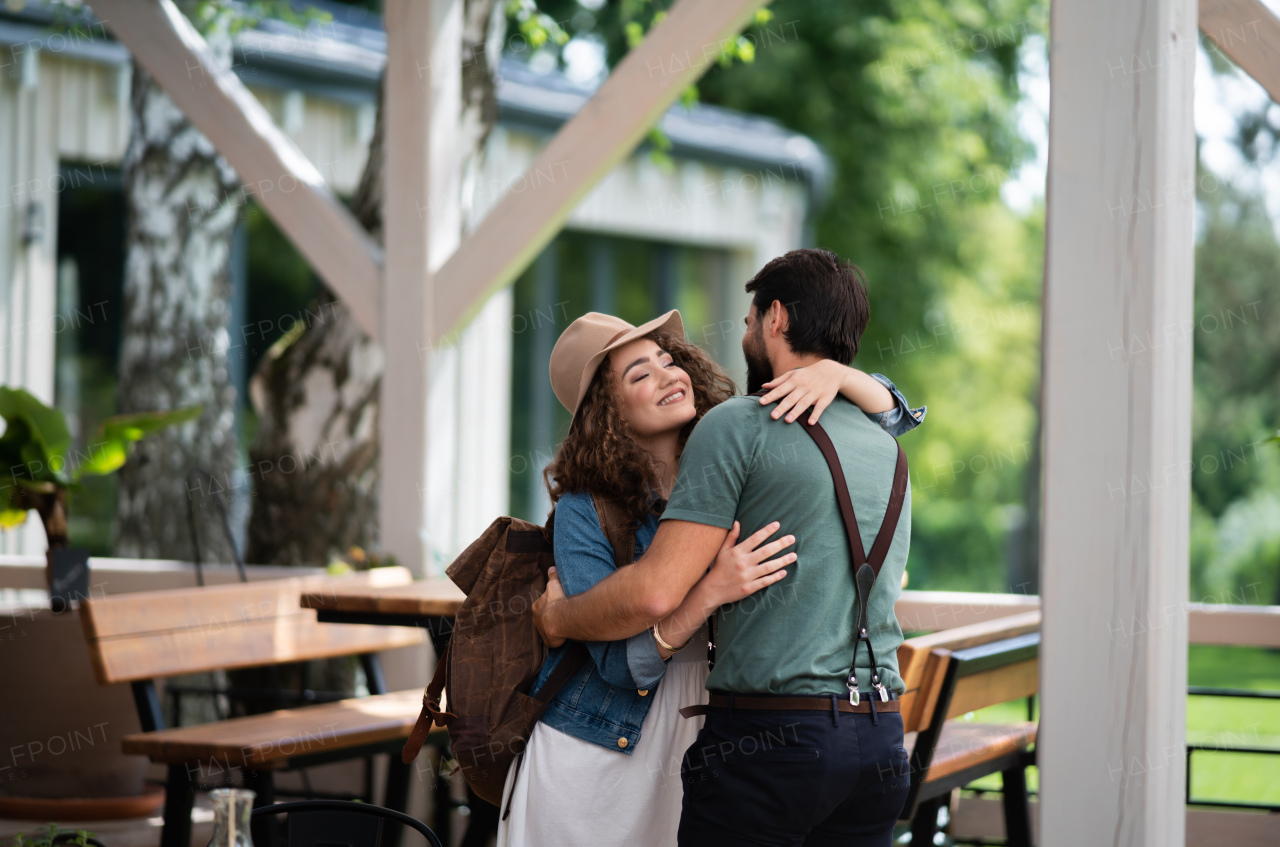 Happy young couple greeting outdoors on terrace restaurant, end of lockdown.