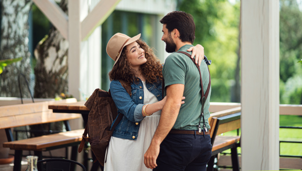 Happy young couple greeting outdoors on terrace restaurant, end of lockdown.