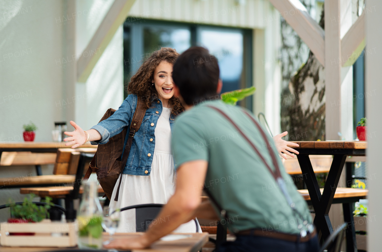 Happy young couple greeting outdoors on terrace restaurant, end of lockdown.