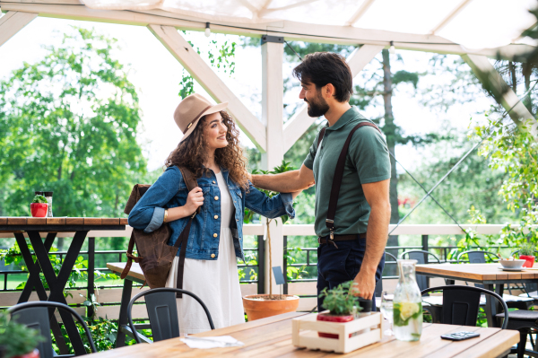 Happy young couple greeting outdoors on terrace restaurant, end of lockdown.