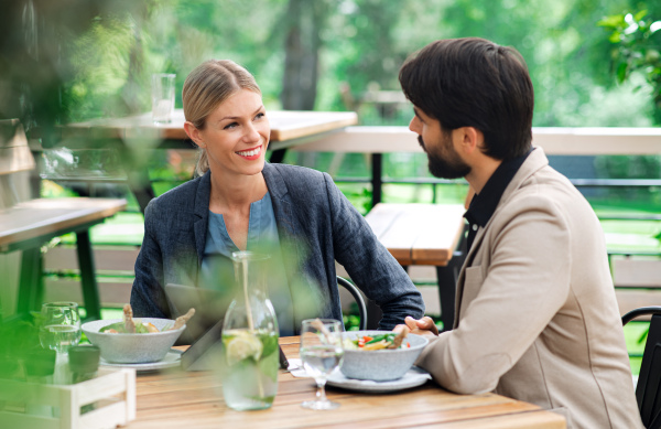 Happy couple sitting at the table outdoors on terrace restaurant, talking.