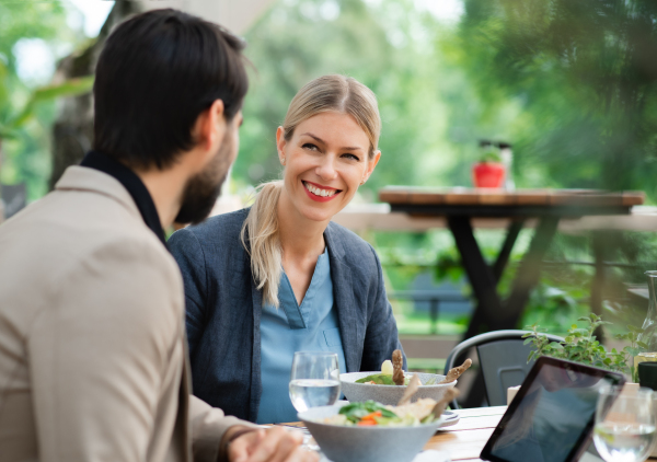 Happy couple sitting at the table outdoors on terrace restaurant, talking.