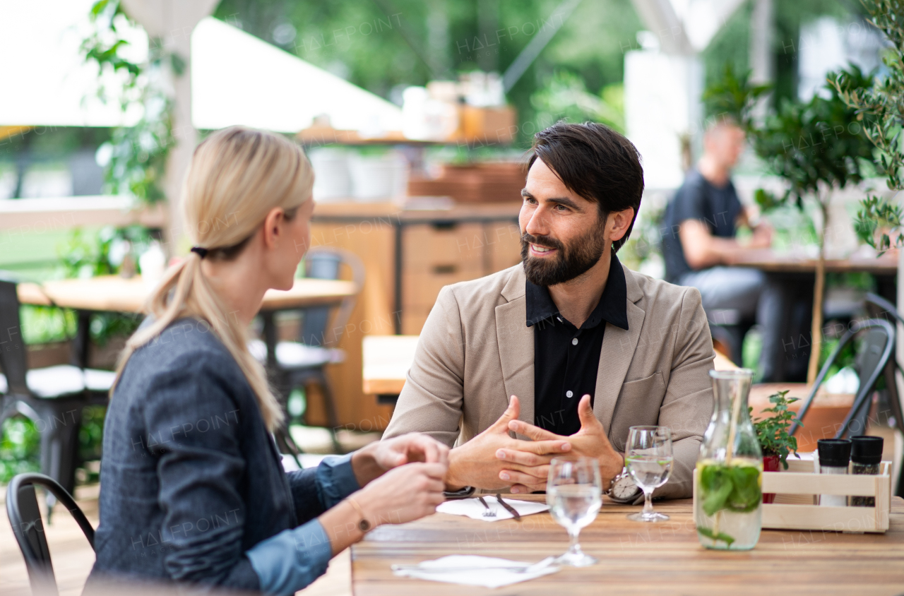 Happy couple sitting at the table outdoors on terrace restaurant, talking.