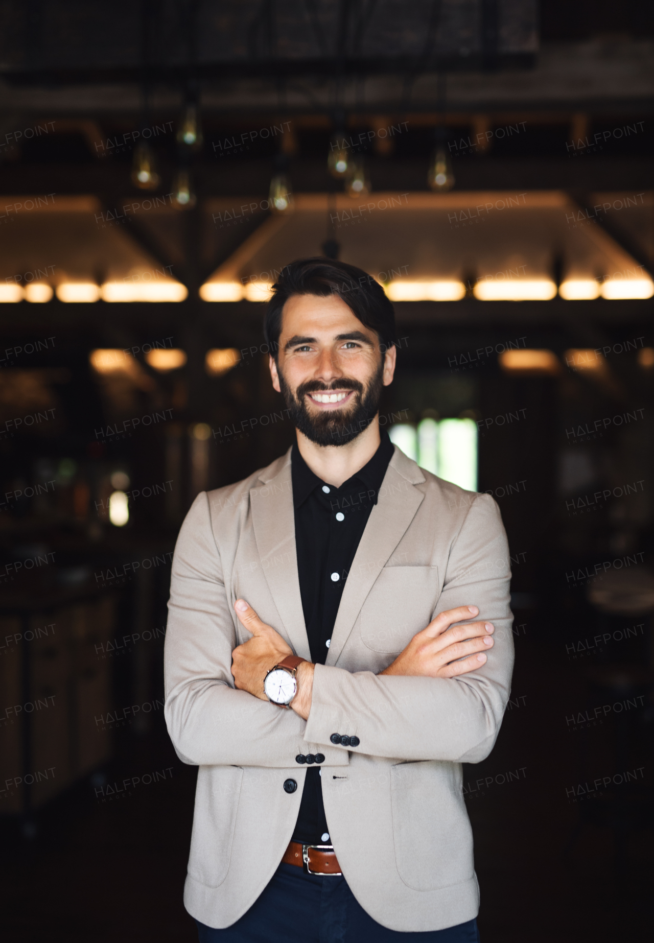 Portrait of businessman with jacket standing indoors in restaurant, looking at camera.