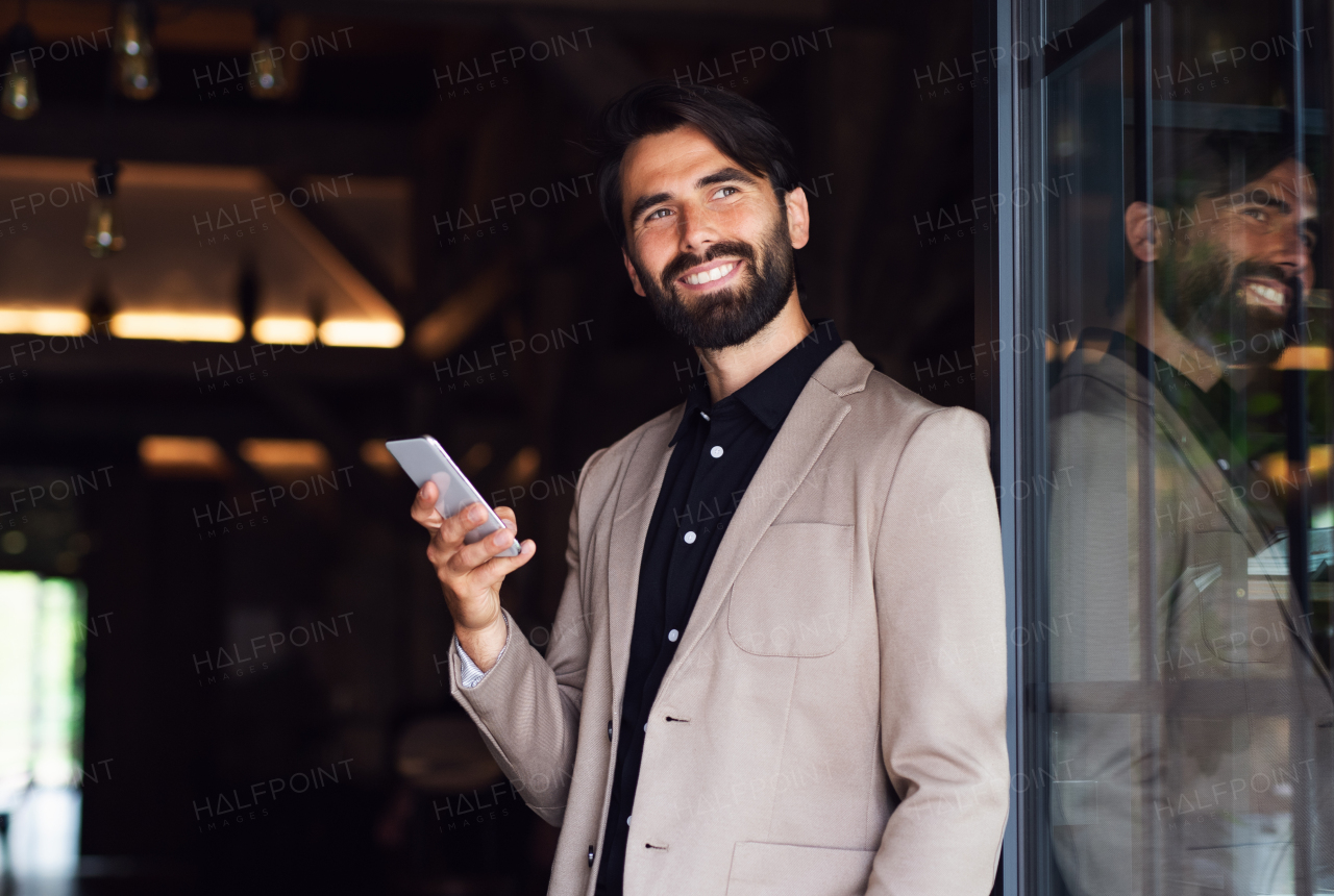 Front view portrait of businessman with jacket standing indoors in restaurant, using telephone.