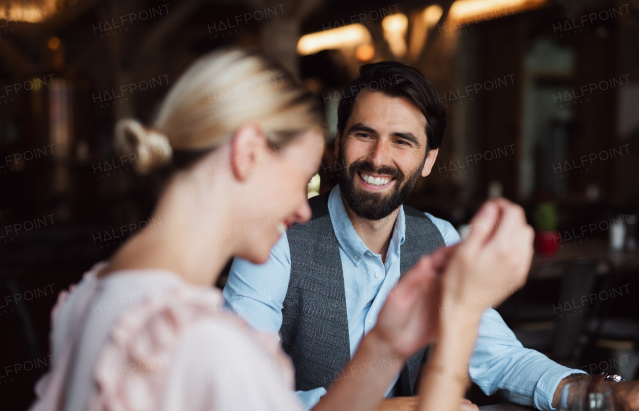 A happy couple sitting indoors in restaurant, talking.