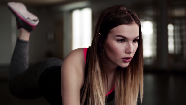 A portrait of a beautiful young girl or woman doing exercise in a gym.