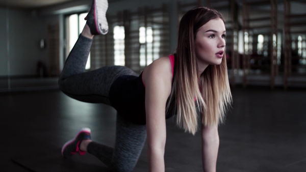 A portrait of a beautiful young girl or woman doing exercise in a gym.