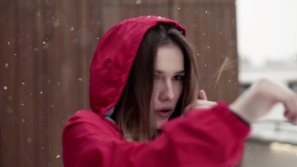 A portrait of young beautiful girl or woman with smartwatch doing exercise outdoors in winter.