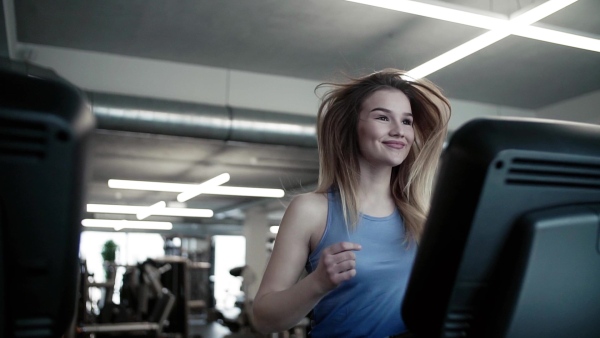 A portrait of a beautiful young girl or woman doing cardio workout in a gym. Slow motion.