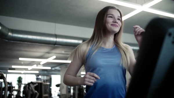 A portrait of a beautiful young girl or woman doing cardio workout in a gym. Slow motion.