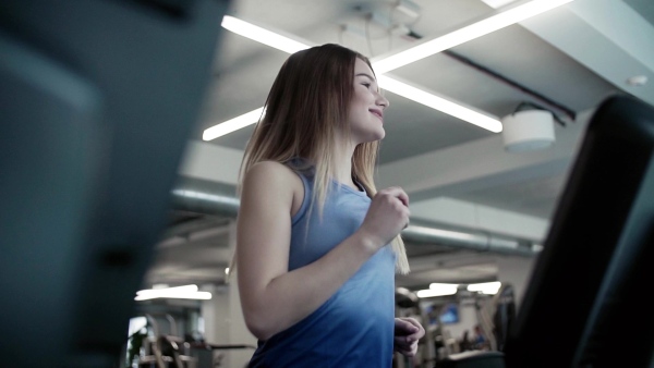 A portrait of a beautiful young girl or woman doing cardio workout in a gym. Slow motion.