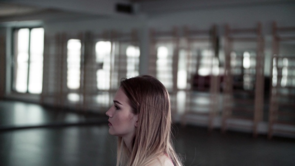 A portrait of a beautiful young girl or woman doing exercise with a kettlebell in a gym. Slow motion.