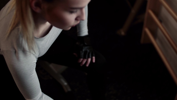 A young girl or woman with dumbbells, doing workout in a gym.