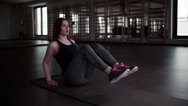 A portrait of a beautiful young girl or woman doing exercise in a gym. Slow motion.