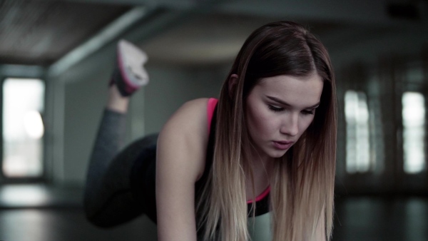 A portrait of a beautiful young girl or woman doing exercise in a gym. Slow motion.