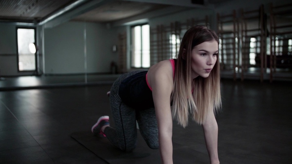 A portrait of a beautiful young girl or woman doing exercise in a gym. Slow motion.